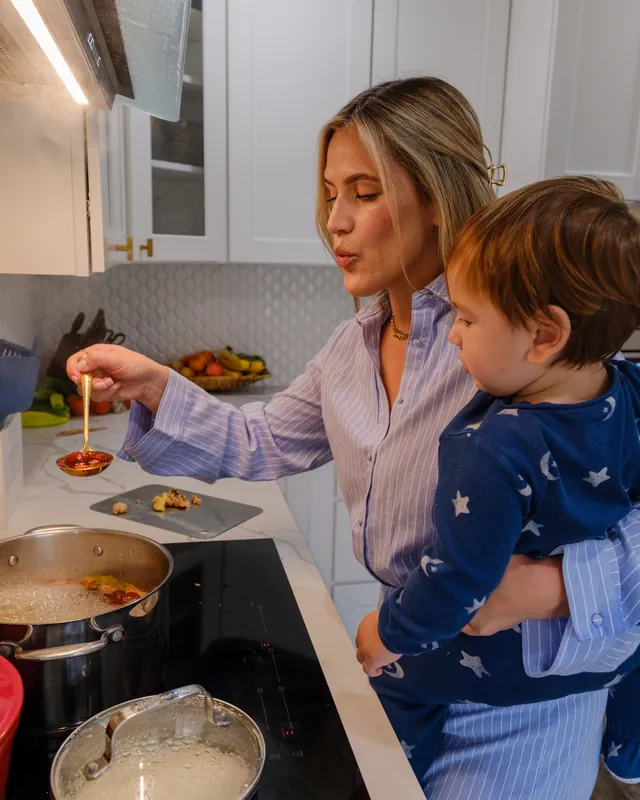 Daniela cooking while holding her child